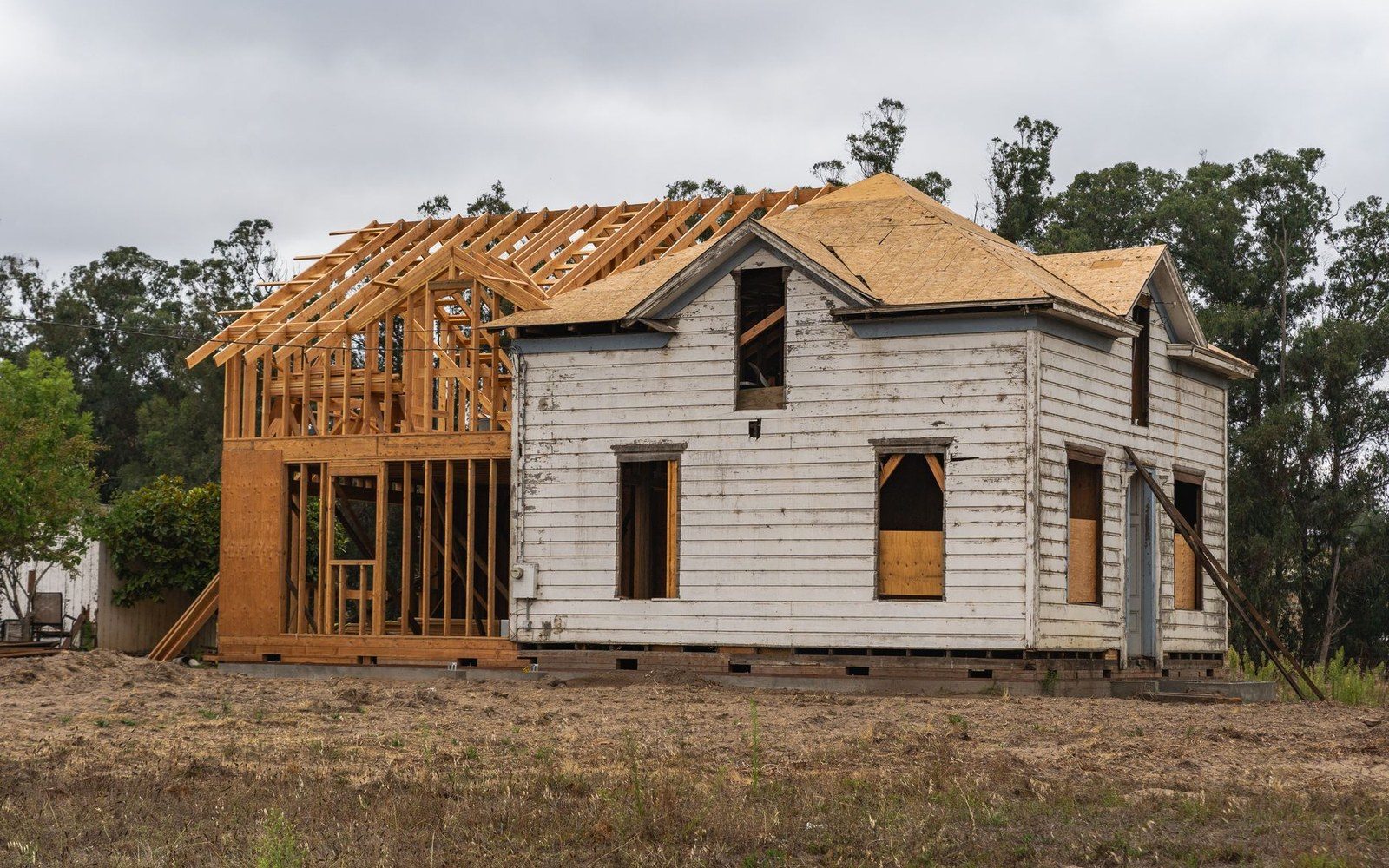 New wood framing extends an old weathered farmhouse under construction